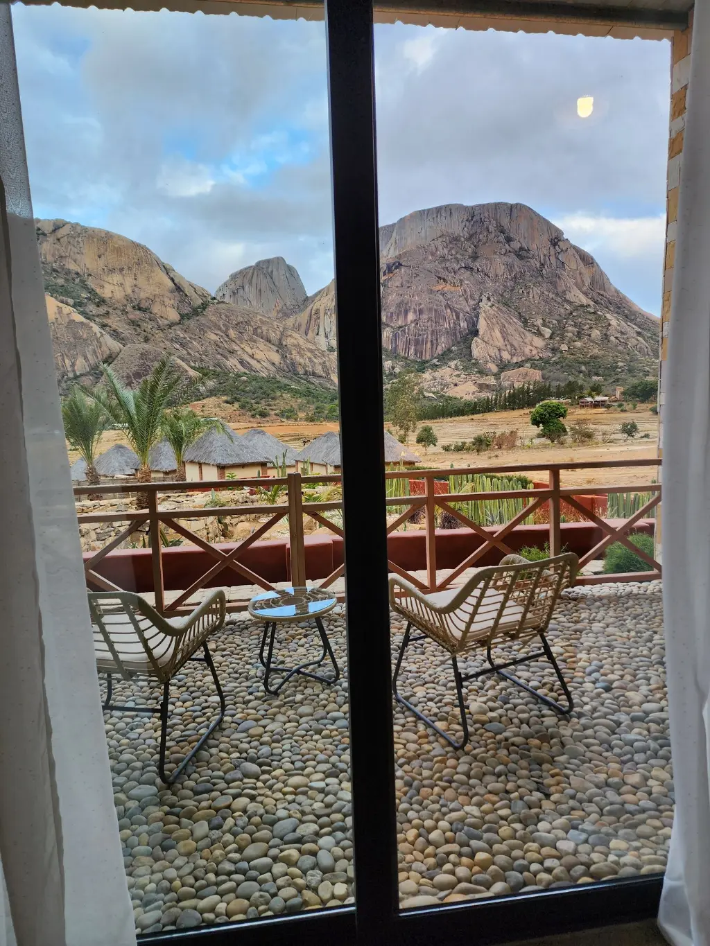Panorama depuis la baie vitrée d’une Suite Signature. Vue rapprochée depuis la baie vitrée d’une Suite Signature de The Anja Reserve Lodge, avec terrasse privée et panorama sur les montagnes granitiques de la Réserve d’Anja à Ambalavao.