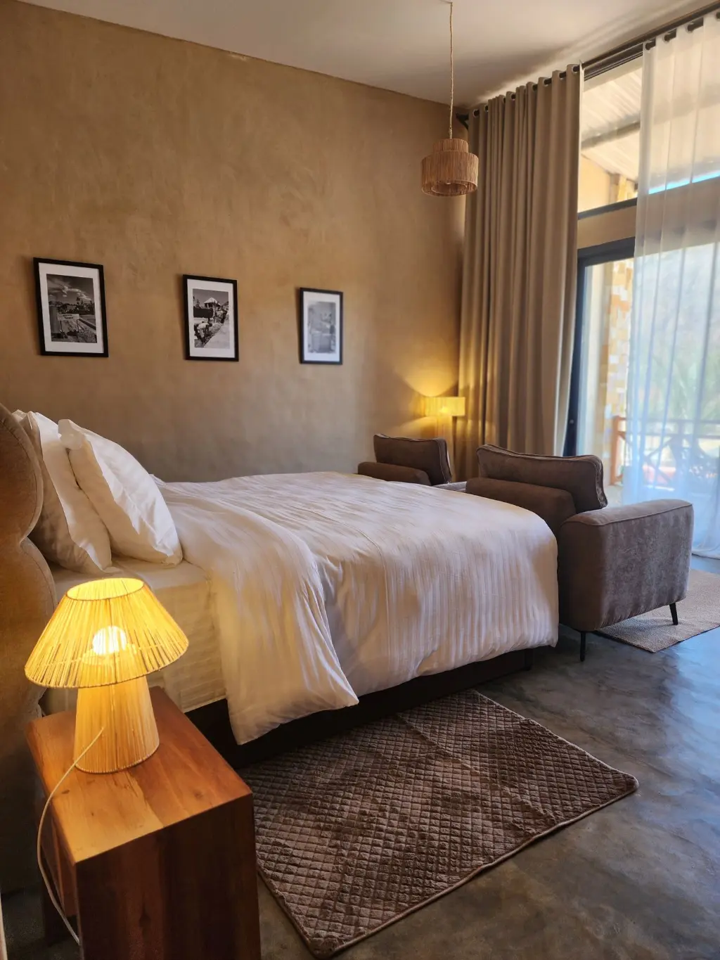 Suite Signature — confort haut de gamme à Anja. Intérieur d’une Suite Signature de The Anja Reserve Lodge à Ambalavao, avec lit haut de gamme, salon privé, rideaux en lin et décoration sobre près de la Réserve d’Anja.